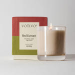 Lit scented candle in a glass tumbler beside its box
