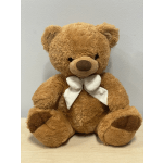 Brown teddy bear with a white bow sitting against a plain background