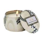 Lit decorative candle in a patterned tin container with lid
