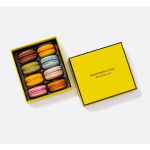 Box of colorful macarons with a yellow lid beside it