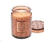 Lit amber candle in a decorative glass jar with a matching lid