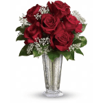 Red roses arranged in a tall silver vase with white filler flowers
