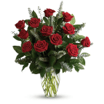 Red roses arranged in a clear glass vase with greenery