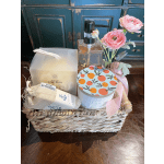 Gift basket with pink flowers, a soap dispenser, candle, and bath items