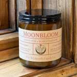 Amber candle jar with a black lid and labeled Moonbloom scent