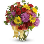 Colorful bouquet of daisies and carnations in a glass vase with a yellow ribbon