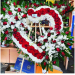 Heart-shaped floral wreath of red roses and white flowers on an easel