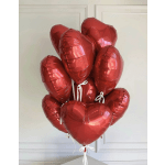 Cluster of red heart-shaped balloons tied with white ribbons