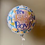 Round foil balloon reading "It's A Baby Boy!" with blue and yellow hearts