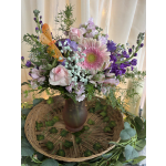 Pink and purple mixed bouquet in a brown vase with an orange butterfly