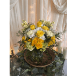 Yellow roses and white flowers in a glass vase with candles