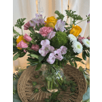 Mixed bouquet of pink, yellow, and white flowers in a glass vase