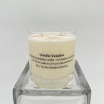Cream-colored vanilla candle in a clear glass jar on a square glass stand