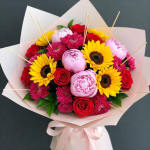 Bouquet of sunflowers, red roses, and pink peonies wrapped in pale paper