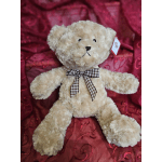 Plush teddy bear with a checkered bow on a red patterned background