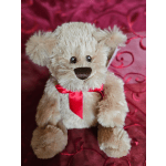 Plush teddy bear with a red ribbon on a pink satin background