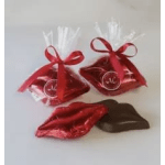 Two red ribbon-tied gift bags with chocolates and a red foil lips-shaped candy
