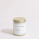 Glass jar candle with a gold lid and white label