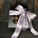 Black gift box tied with a silver ribbon and filled with chocolates.