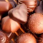 Assorted chocolate truffles, including heart-shaped pieces, in close-up.