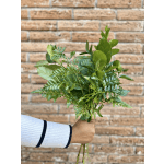 Handheld bunch of assorted green foliage against a brick wall