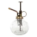Clear glass plant mister with a brass-colored pump and nozzle