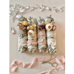 Four small dried flower bundles wrapped in ribbon and lace with scissors nearby