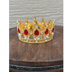 Gold jeweled crown with red and clear stones on a wooden surface