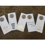 Five greeting card sleeves with gold and black text on a textured surface.