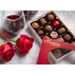 Red roses beside a box of assorted chocolates and a glass of red wine