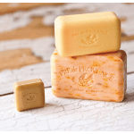 Three bars of soap stacked on a rustic surface.