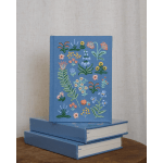 Three blue books with embroidered floral covers stacked on a table