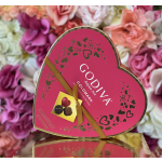 Heart-shaped Godiva chocolate box with pink flowers in the background