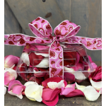 Clear gift box filled with pink and white rose petals, tied with a pink heart ribbon.
