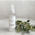 Eucalyptus shower mist spray bottle beside a eucalyptus sprig