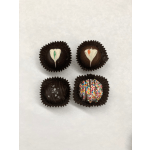 Four decorated chocolate truffles in dark paper cups on a white background