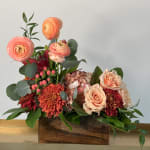 Mixed floral arrangement in a wooden box with peach and red blooms