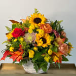 Basket arrangement with sunflowers, roses, and chrysanthemums in autumn colors