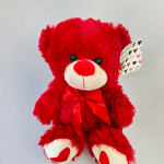 Red teddy bear with a satin bow and heart-patterned tag