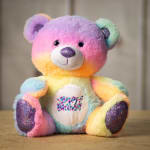 Rainbow plush teddy bear with "Happy Birthday" on its belly