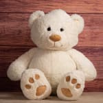 White teddy bear sitting against a wood background