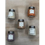 Five scented candles in glass jars arranged on a wooden surface