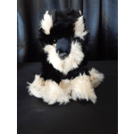 Black-and-white plush dog toy sitting against a dark backdrop