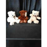 Three teddy bears seated on a black surface against a dark backdrop