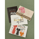 Assorted birthday greeting cards with colorful designs on a green surface