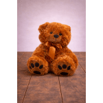 Brown teddy bear with a satin ribbon sitting on a wooden surface