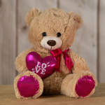 Teddy bear holding a pink heart with "LOVE" text