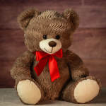 Brown teddy bear with a red ribbon bow