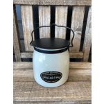 White candle jar with black lid and handle on a wooden chair