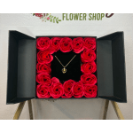 Red roses arranged in a black gift box around a necklace